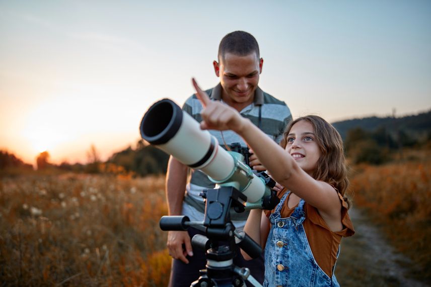 father and daughter examining the night sky telescope astrology