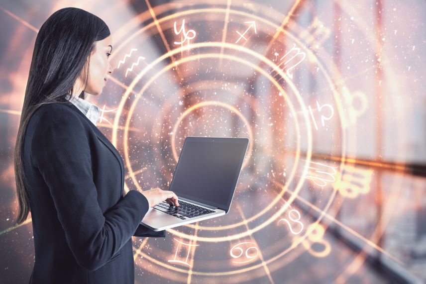 woman in tech on laptop with a zodiac wheel in the background