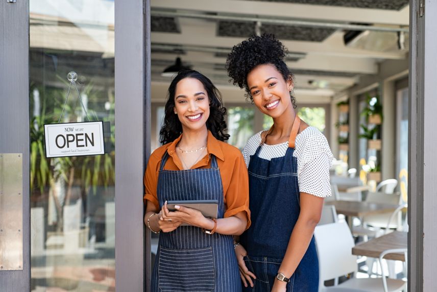 Two entrepreneurs standing in the door of their successful restaurant