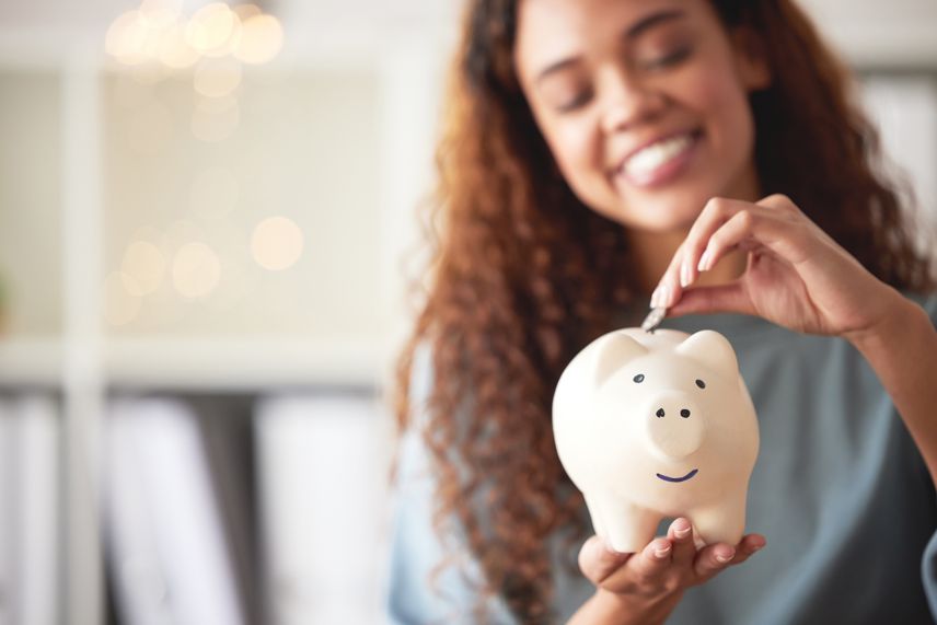 young woman putting money into a piggy bank